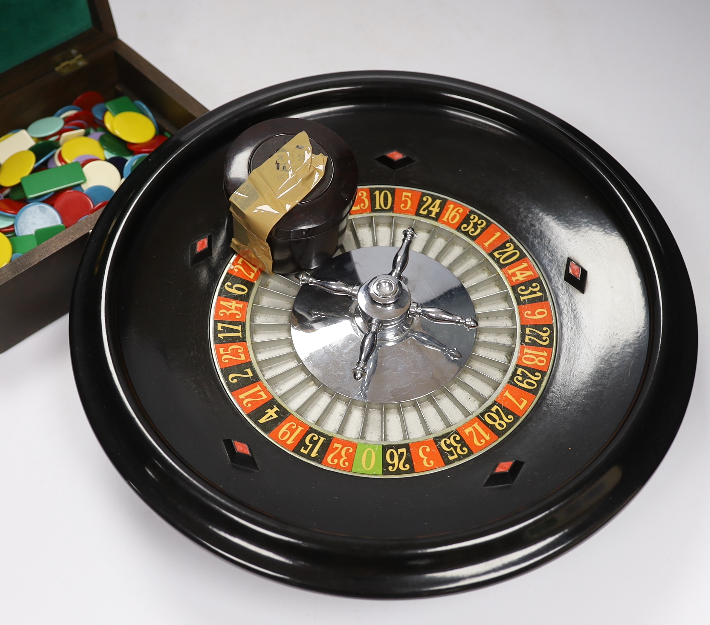 A vintage roulette wheel with gaming counters etc.